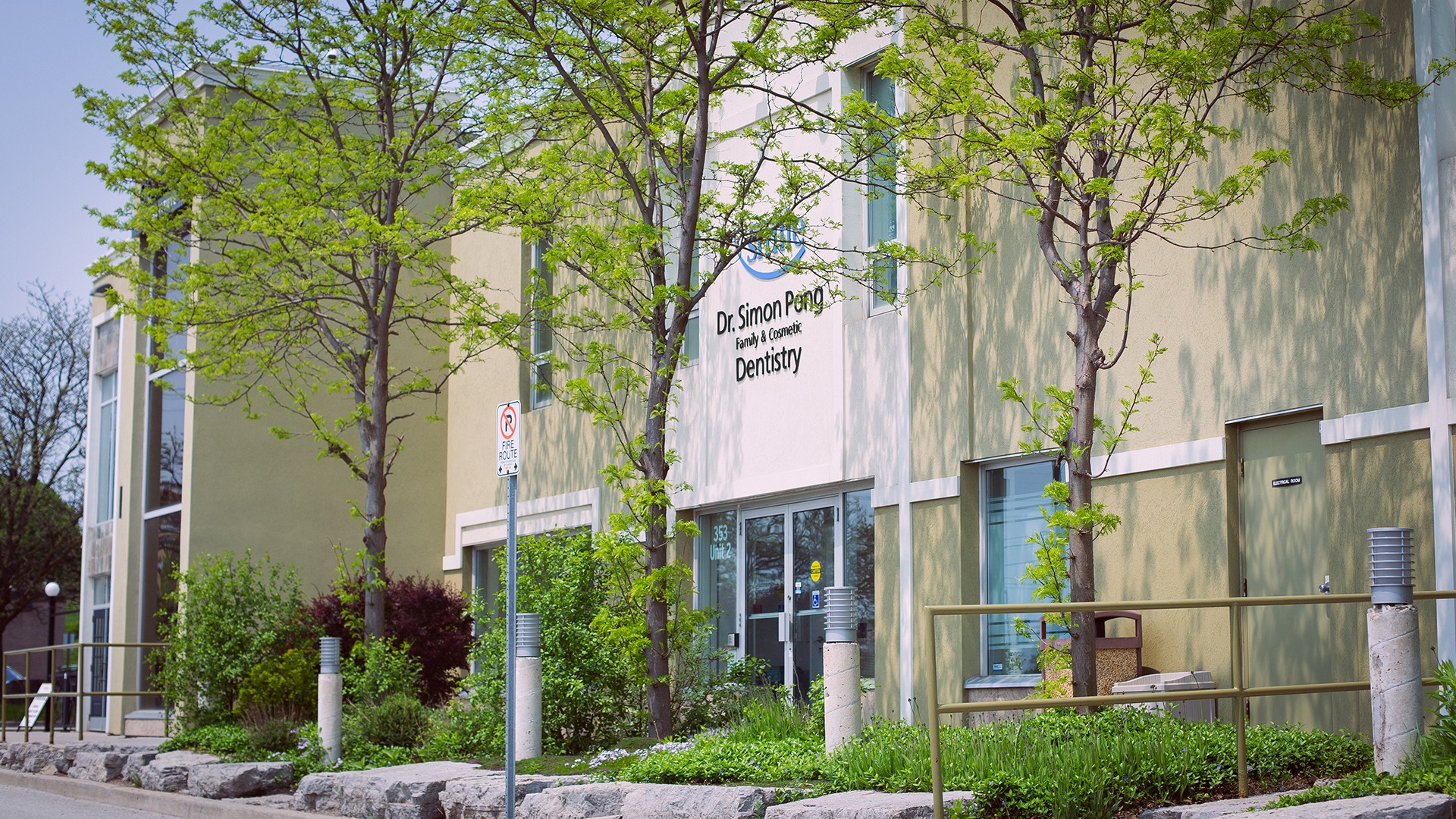 A dental office with green trees in front, displaying "Dr. Simon Pong Family & Cosmetic Dentistry" on its sign.