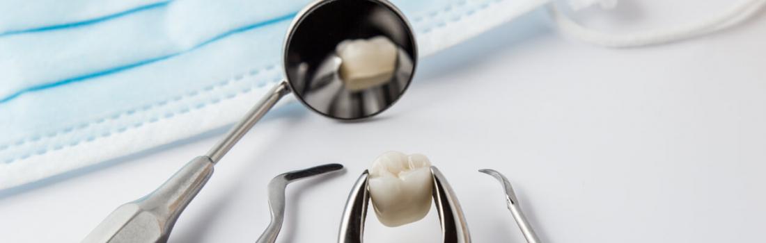 Dental tools and a tooth in focus, with a face mask in the background, reflecting the context of dental care and hygiene.